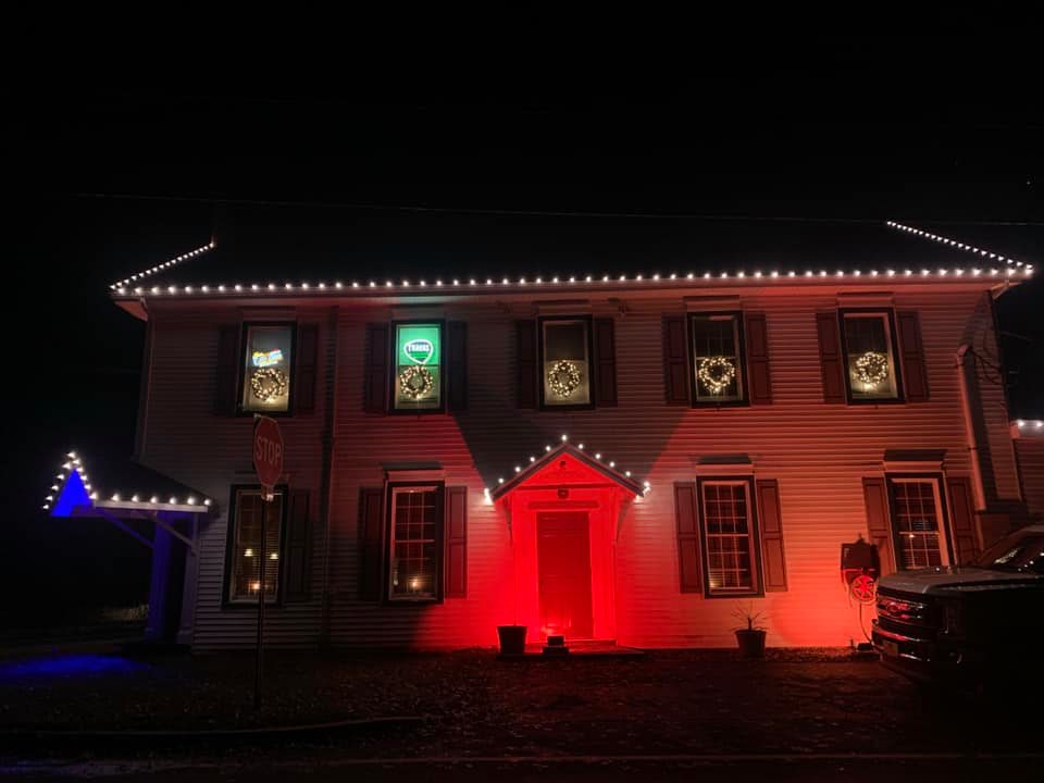 large house with red light on front door, wreathes on windows